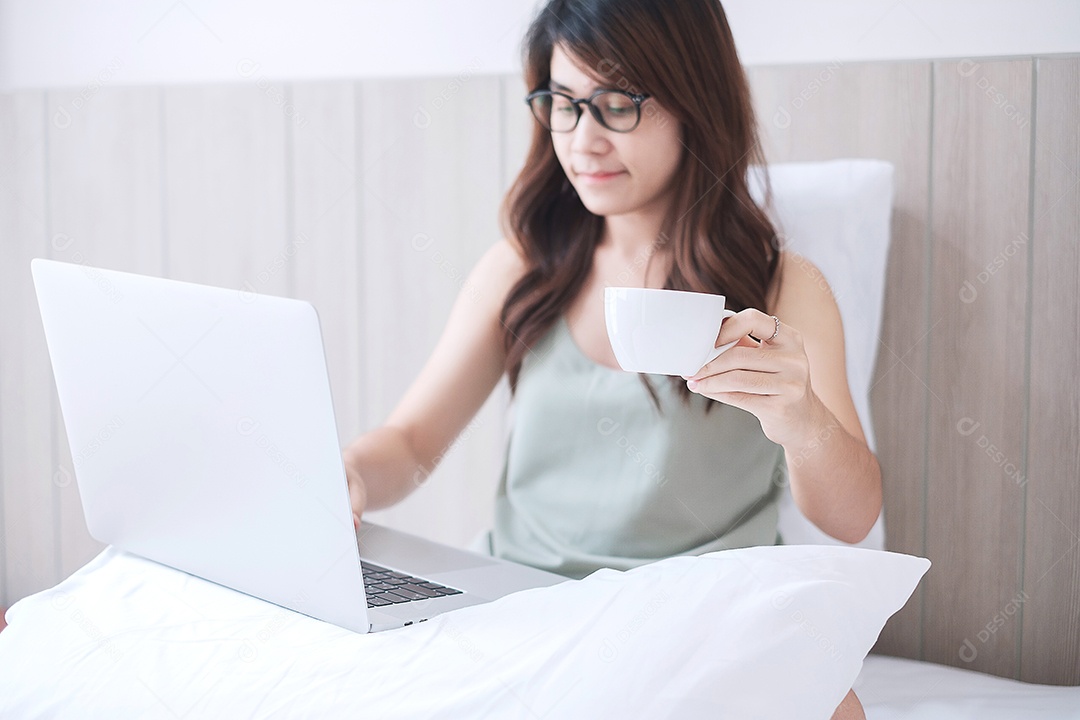 mulher casual segurando a xícara de café enquanto estiver usando computador laptop
