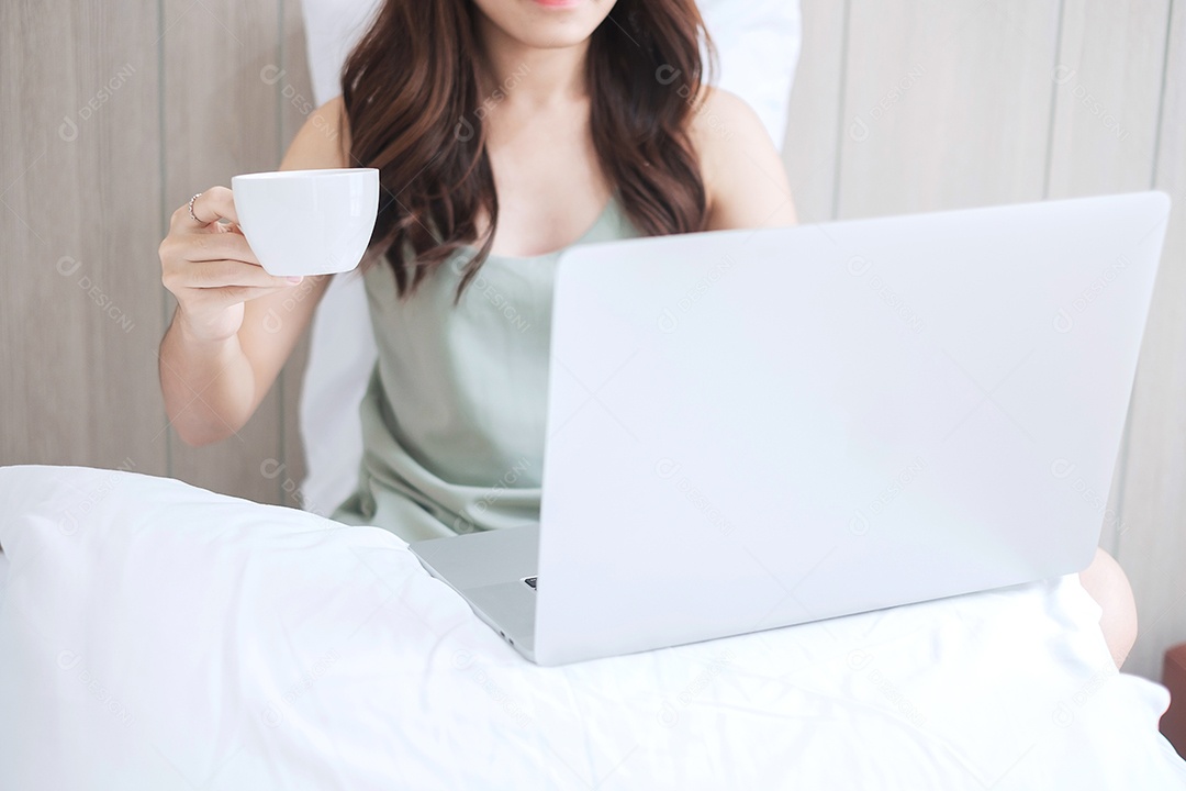 mulher casual segurando a xícara de café enquanto estiver usando computador laptop