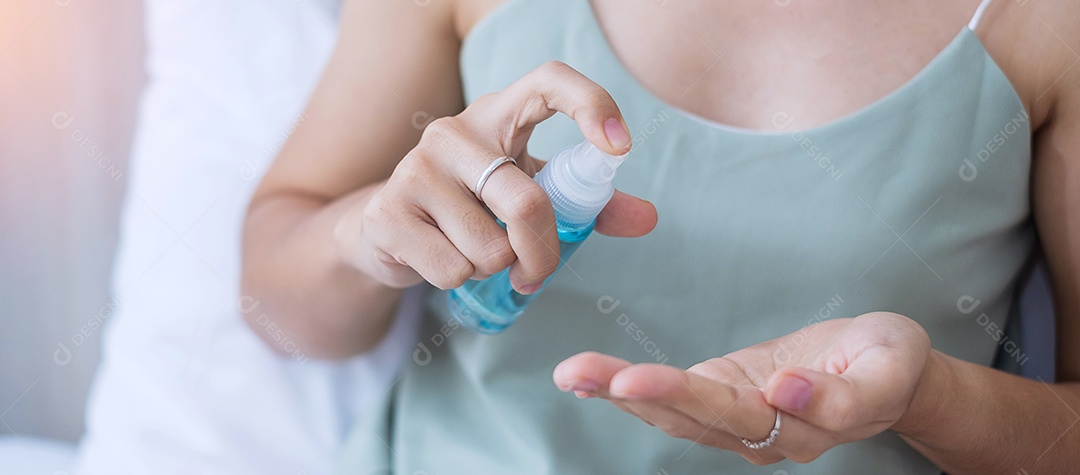 Mulher limpando as mãos com álcool gel desinfetante na cama durante a vigília