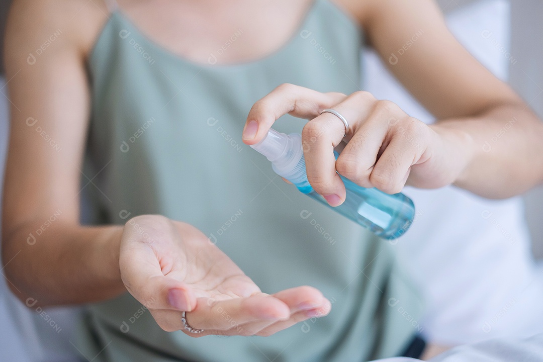 Mulher limpando as mãos com álcool gel desinfetante na cama durante a vigília