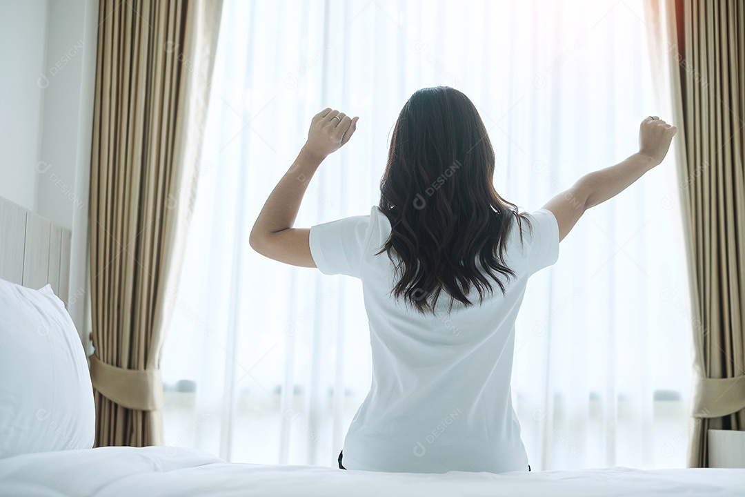 mulher feliz, estendendo-se na cama depois de acordar, fêmea adulta jovem