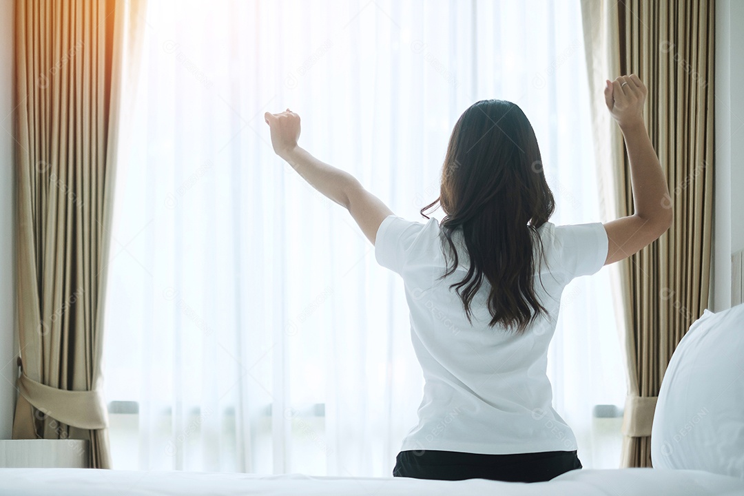 mulher feliz, estendendo-se na cama depois de acordar, fêmea adulta jovem
