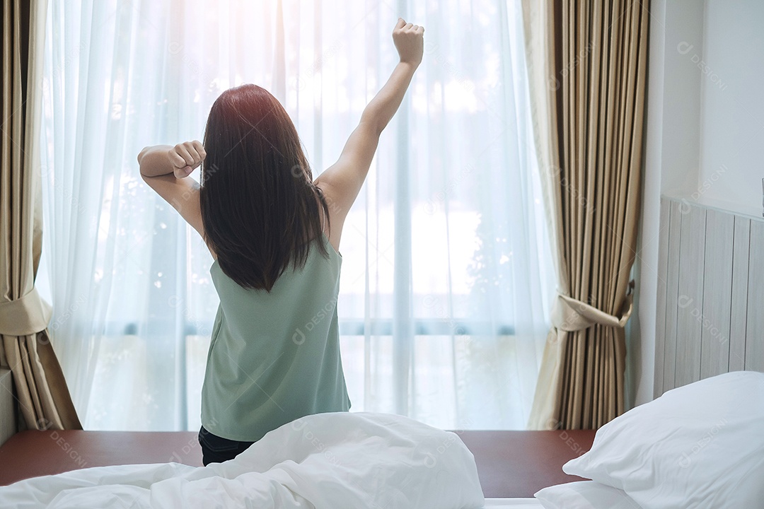 mulher feliz, estendendo-se na cama depois de acordar, fêmea adulta jovem