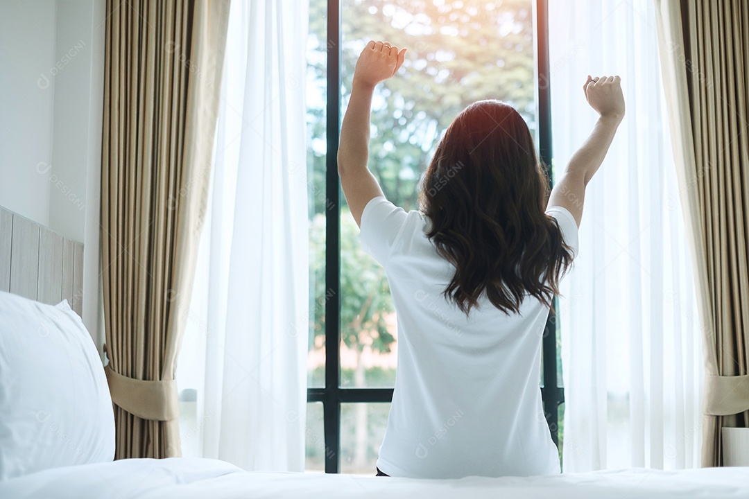 mulher feliz, estendendo-se na cama depois de acordar, fêmea adulta jovem