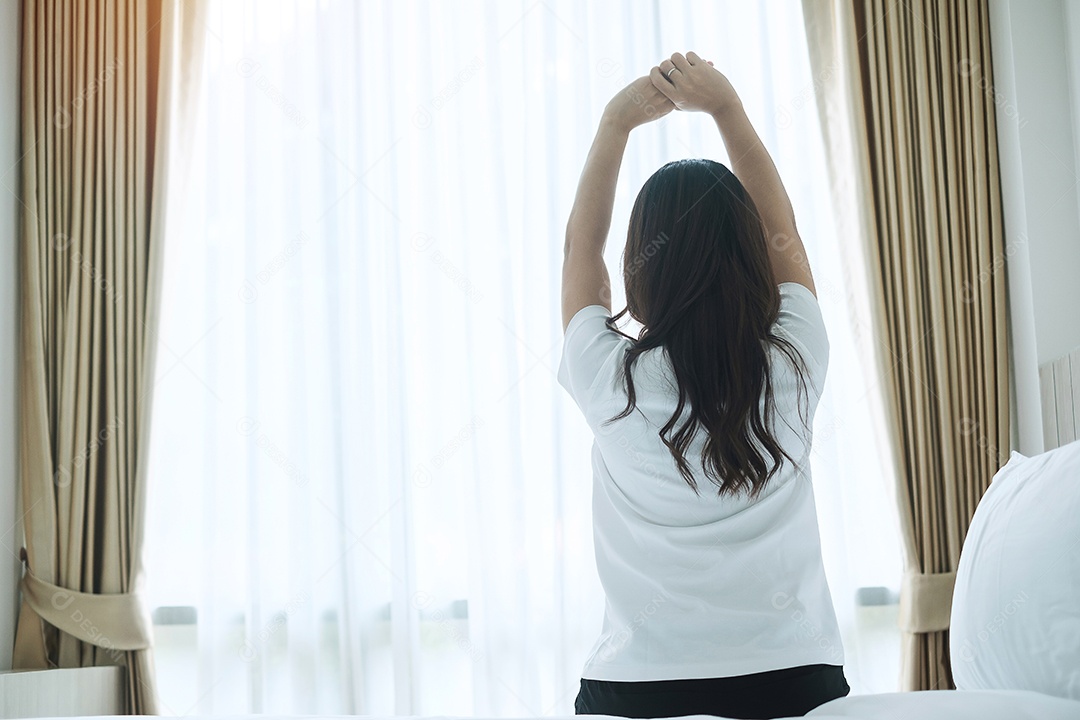 mulher feliz, estendendo-se na cama depois de acordar, fêmea adulta jovem