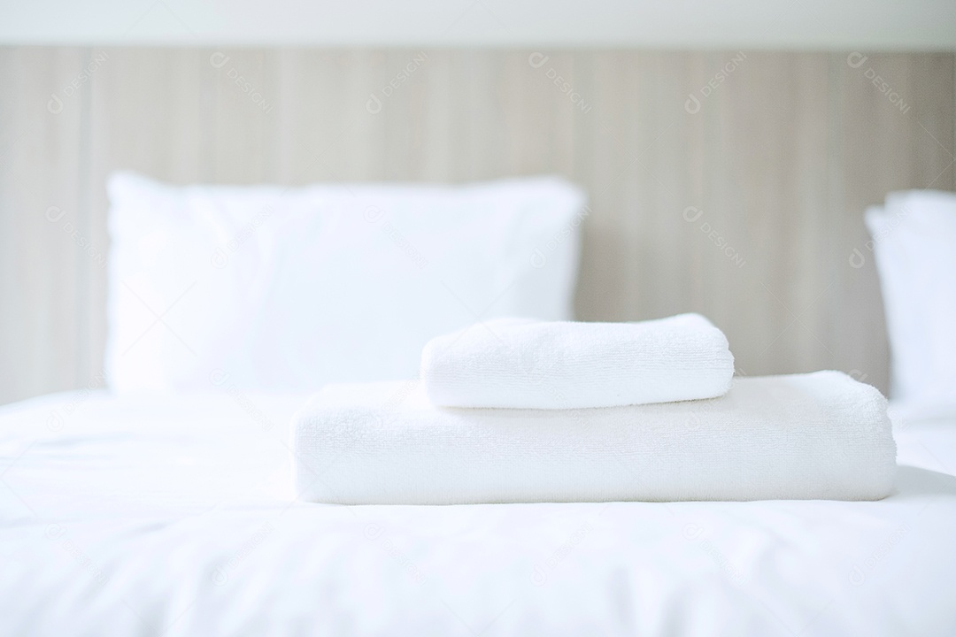 Pilha de toalha branca e roupão de banho na cama em hotel de luxo ou reso