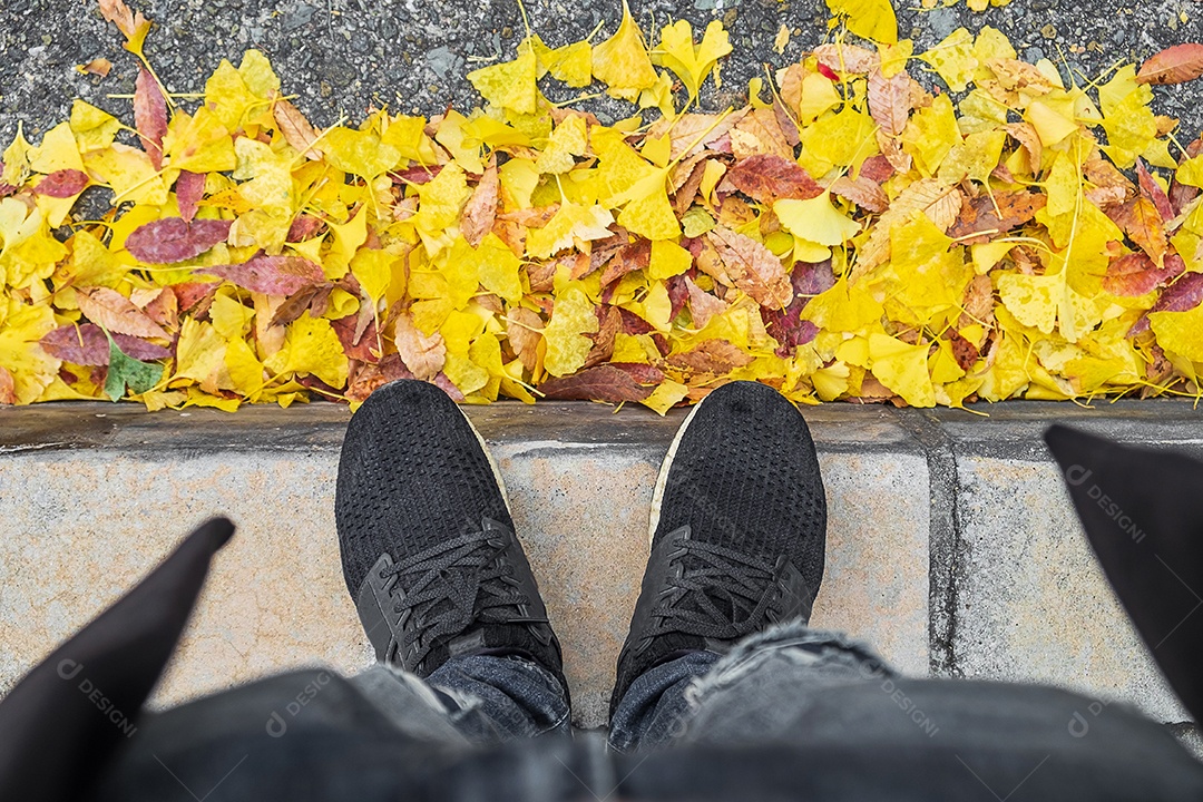 Homem de casaco de inverno e tênis em cima de bilob de ginkgo amarelo