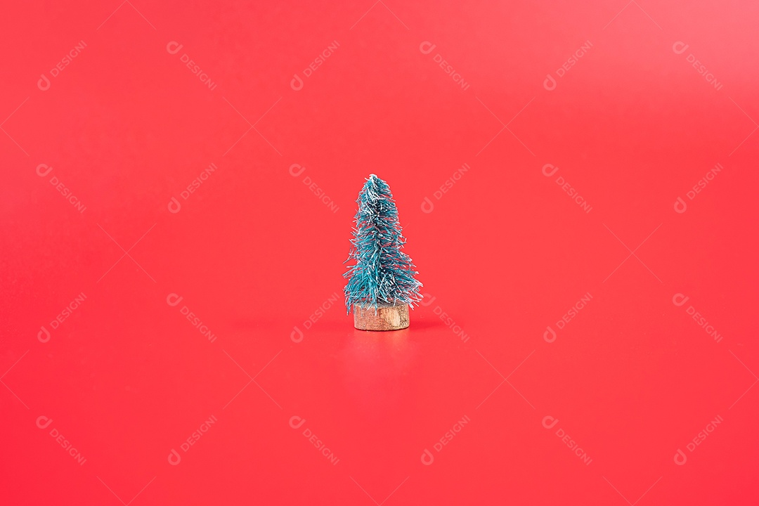 Feliz Natal com árvore de Natal em miniatura sobre fundo vermelho.
