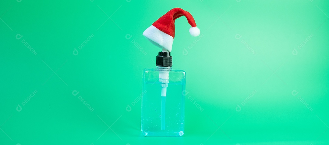 Feliz Natal com chapéu de Papai Noel e garrafa de gel desinfetante para as mãos contra coronavírus ou doença do vírus Corona (Covid-19). Conceito de férias, higiene, novo normal e saúde