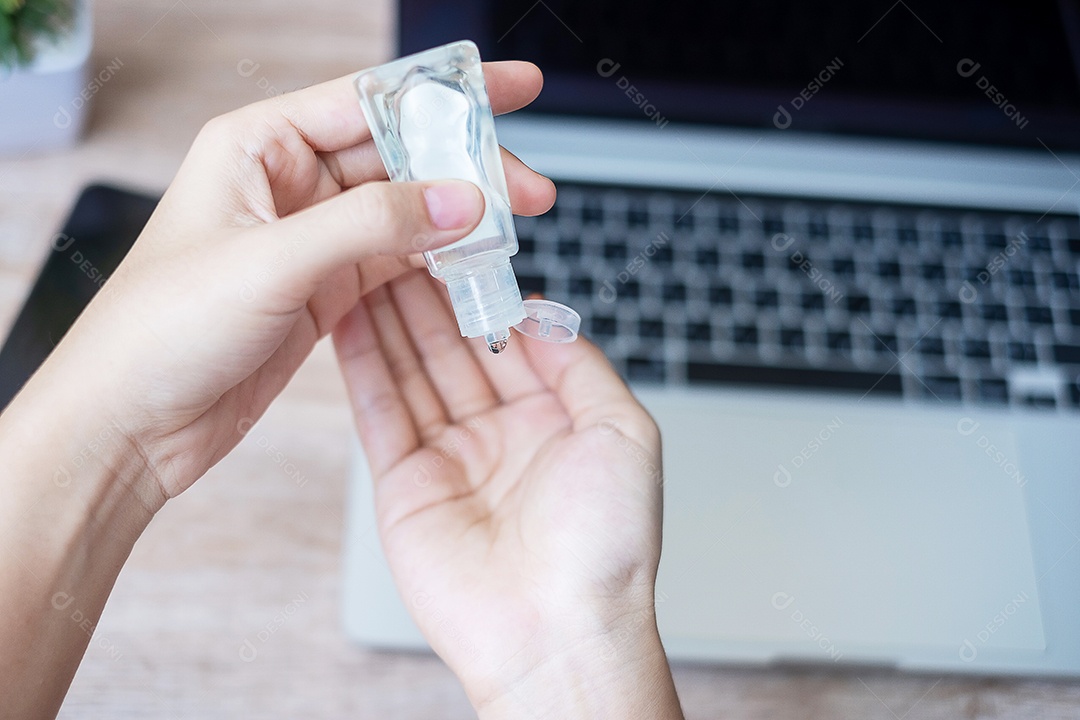 Mulher limpando as mãos por desinfetante de gel de álcool sobre laptop e sm