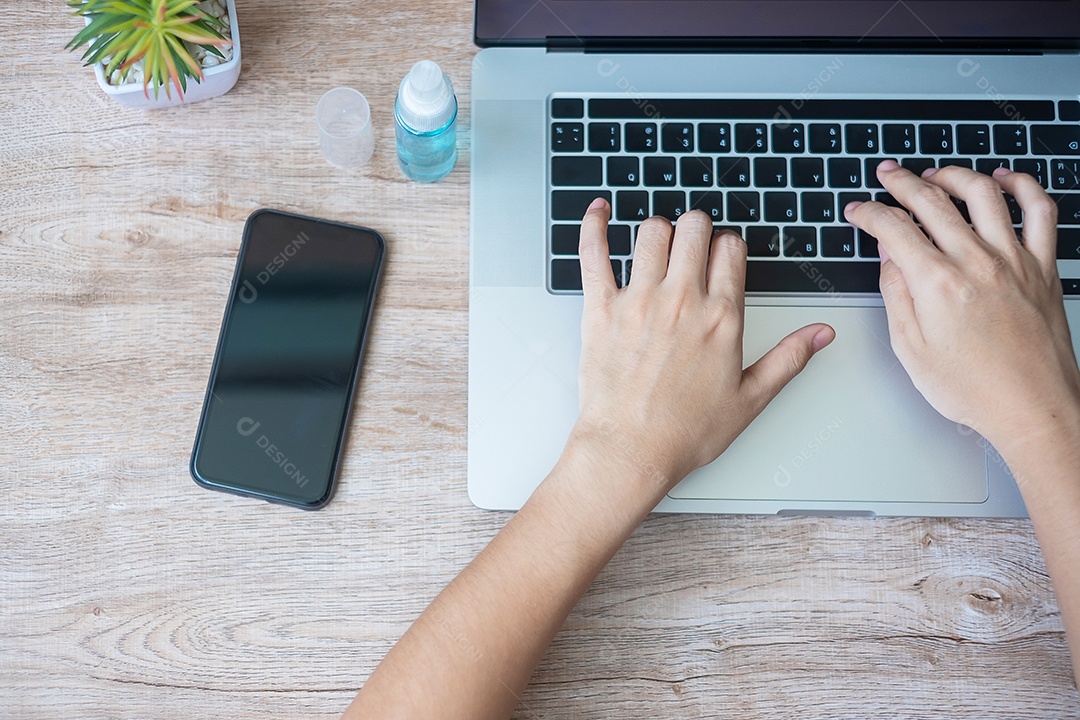 Mulher usando laptop e smartphone durante o trabalho em casa com álcool