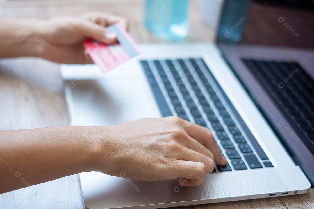 mulher segurando cartão de crédito e usando laptop para compras online