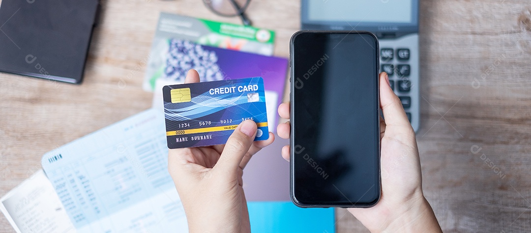 mulher segurando cartão de crédito e usando celular para compras online