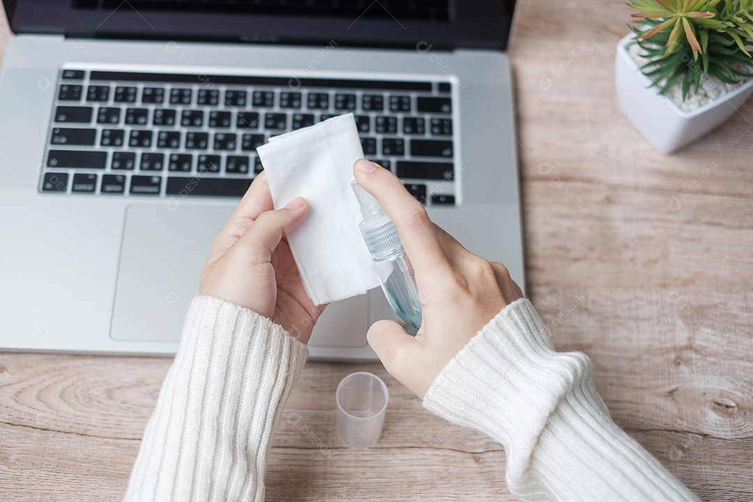 Mulher limpando laptop por lenços umedecidos e álcool desinfetante