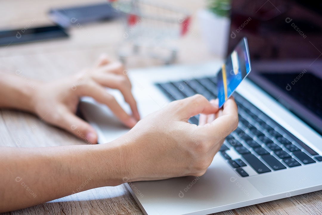 mulher vestindo suéter segurando cartão de crédito e usando laptop