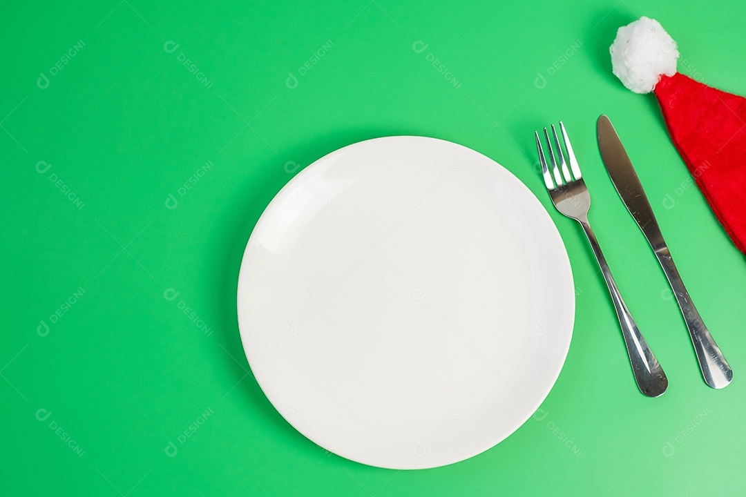 prato branco, garfo e faca sobre fundo verde. Feliz Natal