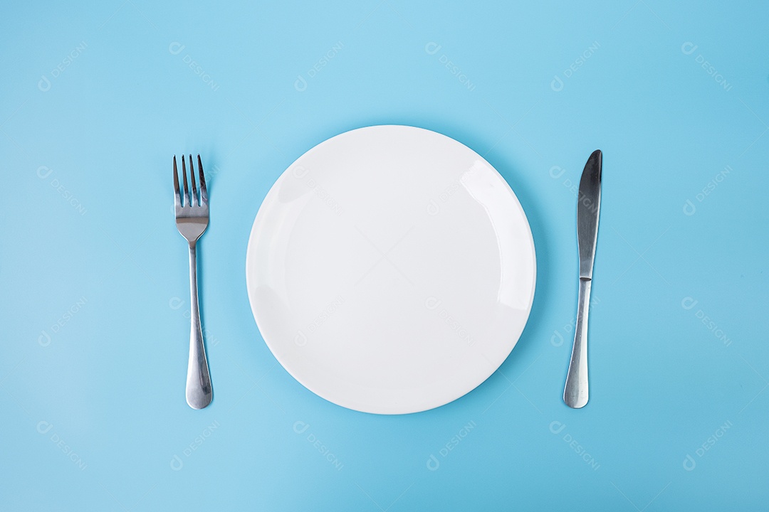 prato de cerâmica branco vazio com faca e garfo em background azul