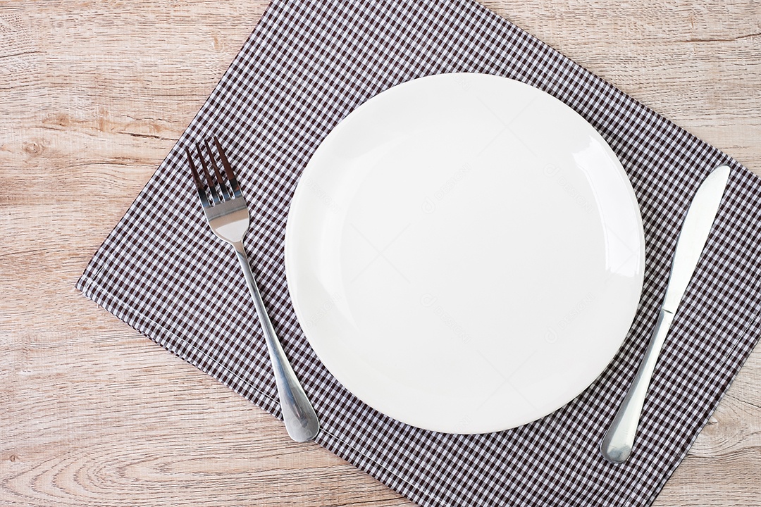 prato de cerâmica branco vazio com faca e garfo no fundo da mesa. conceito de jantar e utensílios de cozinha