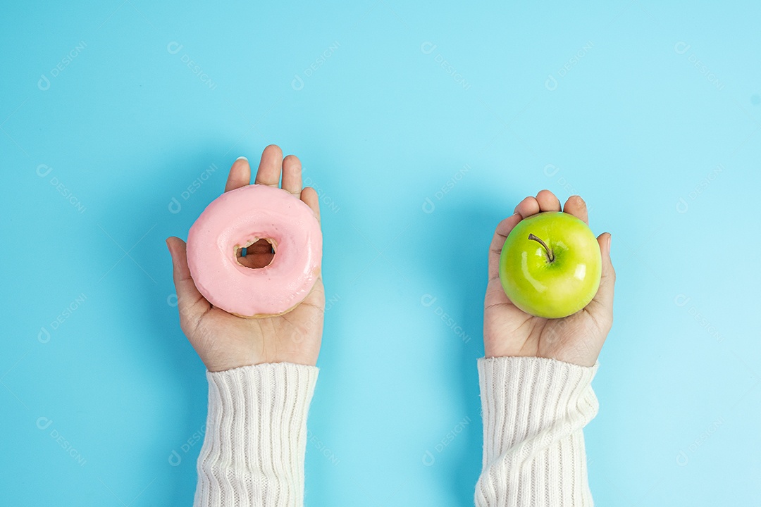 mulher segurando maçã vermelha e rosquinha rosa, a fêmea escolhe entre frutas é comida saudável e doce é junk food não saudável