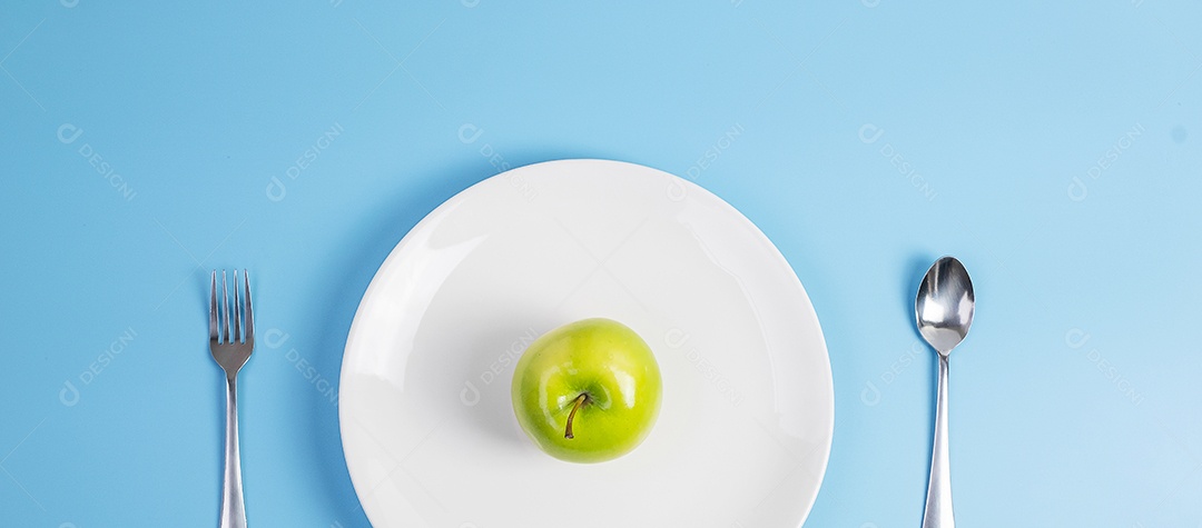Colher e garfo de vista superior, maçã verde na placa de cerâmica branca com fita métrica verde sobre fundo azul. dieta, perda de peso