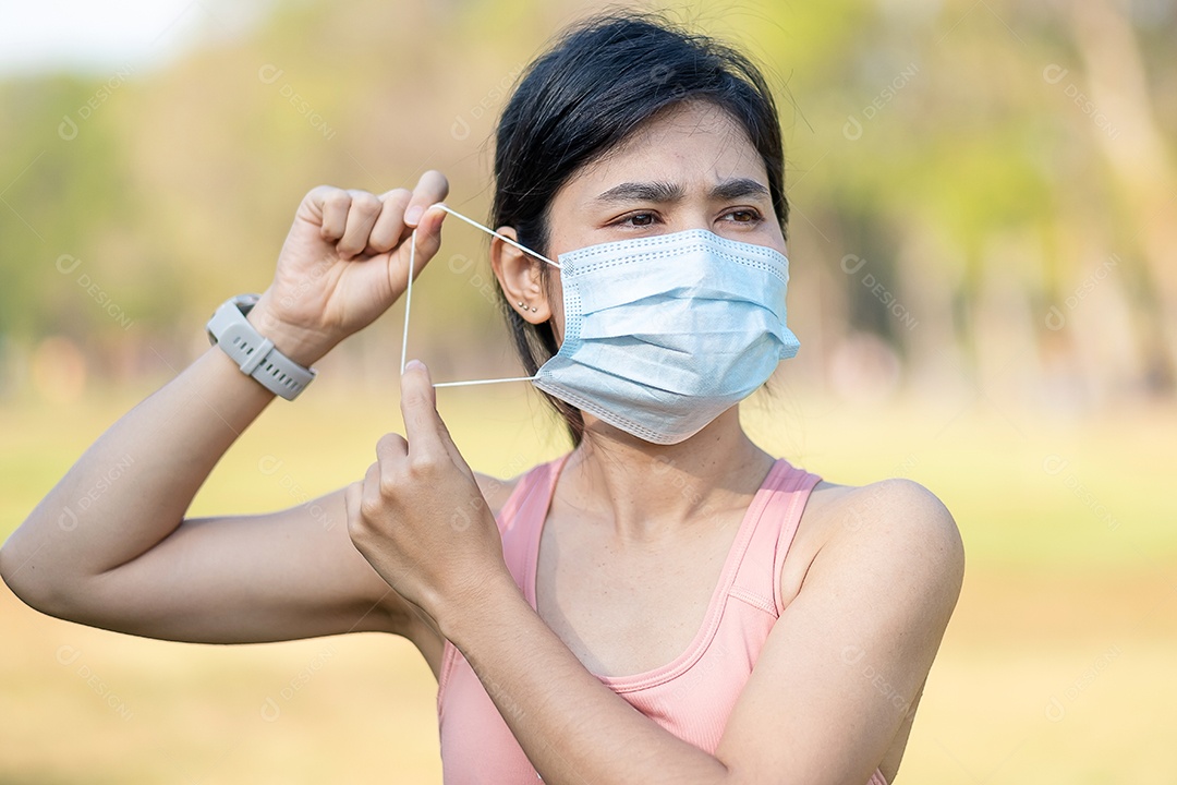 Mulher adulta jovem usando máscara facial protetora durante o alongamento muscular no parque ao ar livre