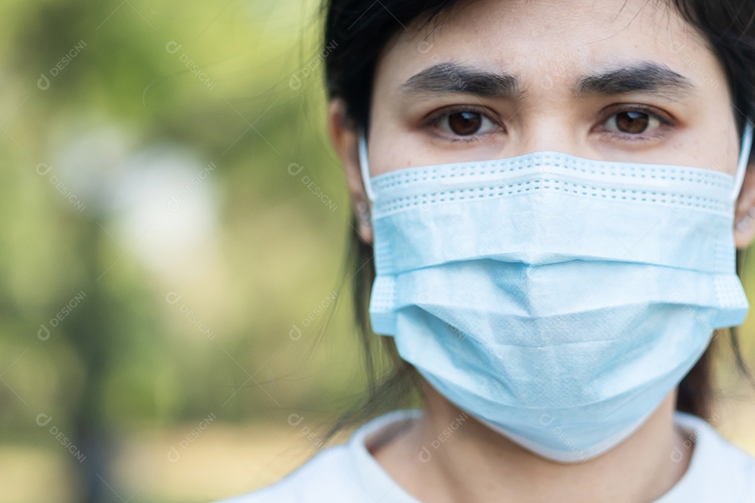 Mulher adulta jovem usando máscara facial protetora durante o alongamento muscular no parque ao ar livre