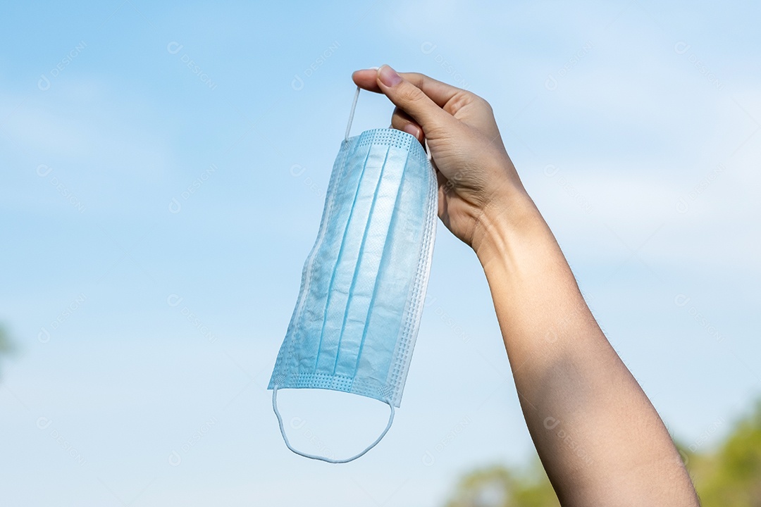 Mão mostrando máscara facial médica protetora no fundo do céu, previne coronavírus ou doença do vírus Corona (Covid-19). novo normal e conceito de saúde