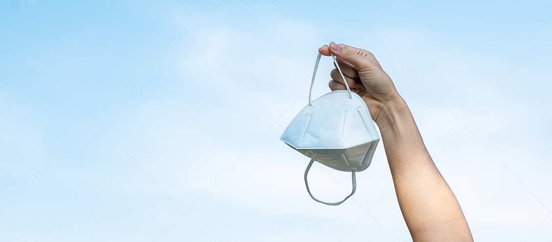 Mão mostrando máscara facial médica protetora no fundo do céu, previne coronavírus ou doença do vírus Corona (Covid-19). novo normal e conceito de saúde