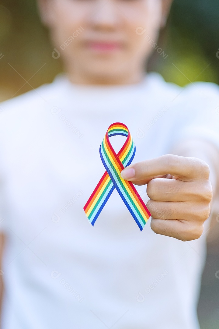 mão mostrando a fita LGBTQ Rainbow contra o fundo do céu pela manhã. Apoie o conceito de Lésbicas, Gays, Bissexuais, Transgêneros, Queer e Direitos