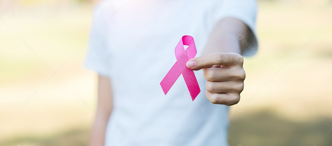 Mês de conscientização do câncer de mama de outubro, mão de mulher adulta segurando a fita rosa para apoiar as pessoas que vivem e estão doentes