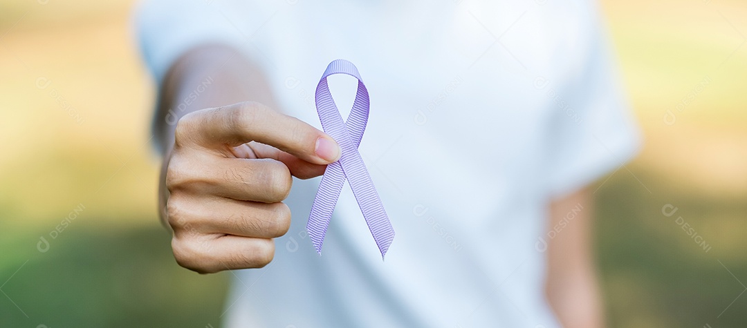 Dia Mundial do Câncer (4 de fevereiro). Mão de uma mulher segurando a fita roxa de lavanda para apoiar pessoas que vivem e doenças. Cuidados de saúde e conceito médico