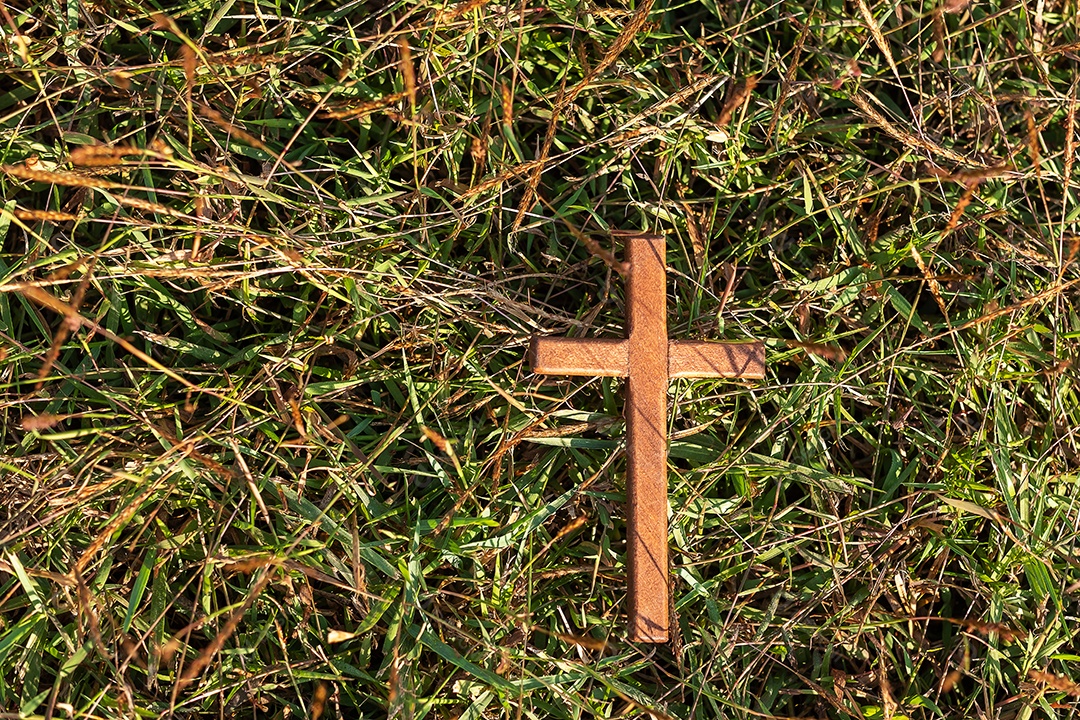 cruz de madeira na grama, ore por bênçãos de Deus. Conceito cristão de religião, crucifixo e fé