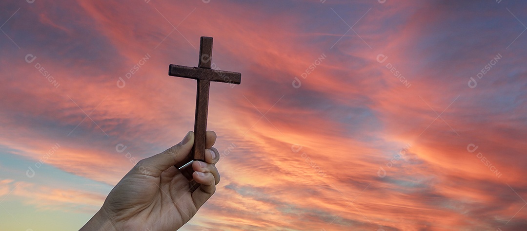 Silhueta mão segurando a cruz de madeira contra o fundo do nascer do sol, palma aberta para cima adoração, orar por bênçãos de Deus