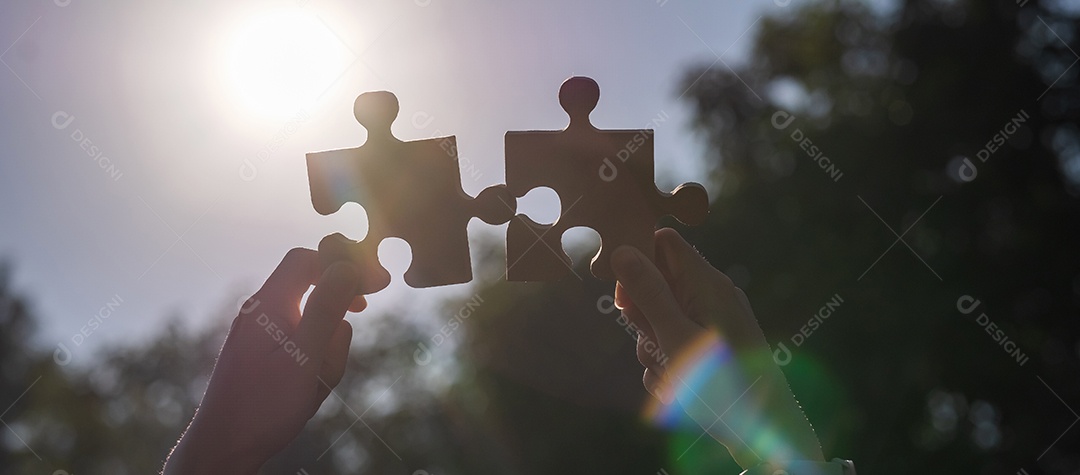 Mãos de mulher conectando a peça do quebra-cabeça de casal contra o efeito do nascer do sol, empresária segurando o quebra-cabeça