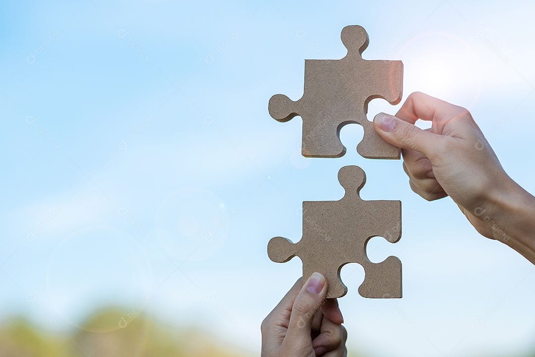 Mãos de mulher conectando a peça do quebra-cabeça de casal contra o efeito do nascer do sol, empresária segurando o quebra-cabeça