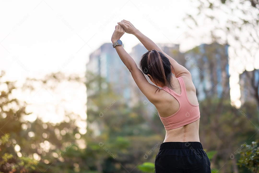 Mulher adulta jovem em sportswear rosa esticando o músculo no parque ao ar livre, esporte mulher aquecer pronto para correr e correr de manhã