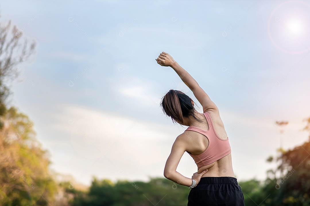 Mulher adulta jovem em sportswear rosa esticando o músculo no parque ao ar livre, esporte mulher aquecer pronto para correr e correr de manhã