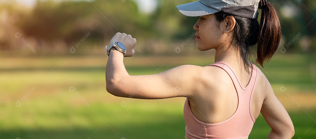 Mulher adulta jovem, verificando o tempo e a frequência cardíaca cardio no smartwatch esportivo durante a corrida no parque ao ar livre