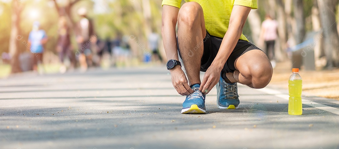 Homem jovem atleta amarrando tênis no parque ao ar livre, corredor masculino pronto para correr na estrada lá fora, asiático Fitness andando