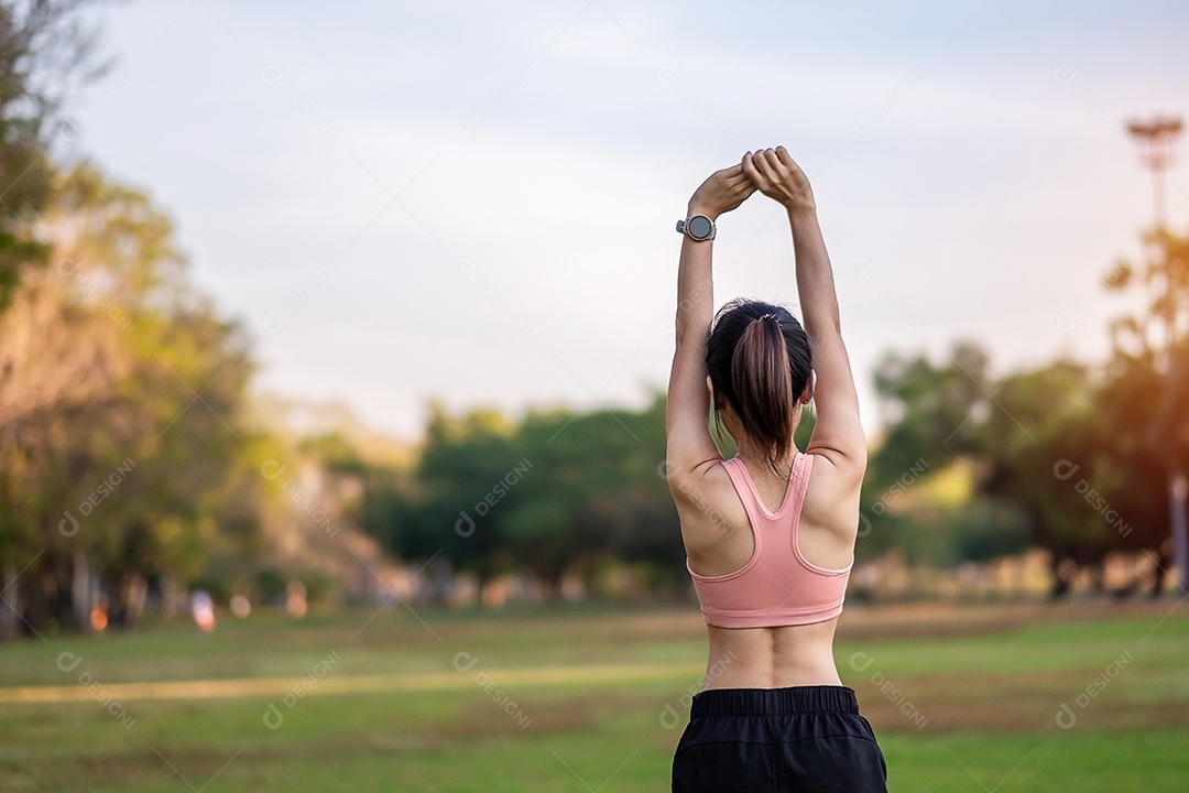 Mulher adulta jovem em sportswear rosa esticando o músculo no parque ao ar livre, esporte mulher aquecer pronto para correr e correr de manhã