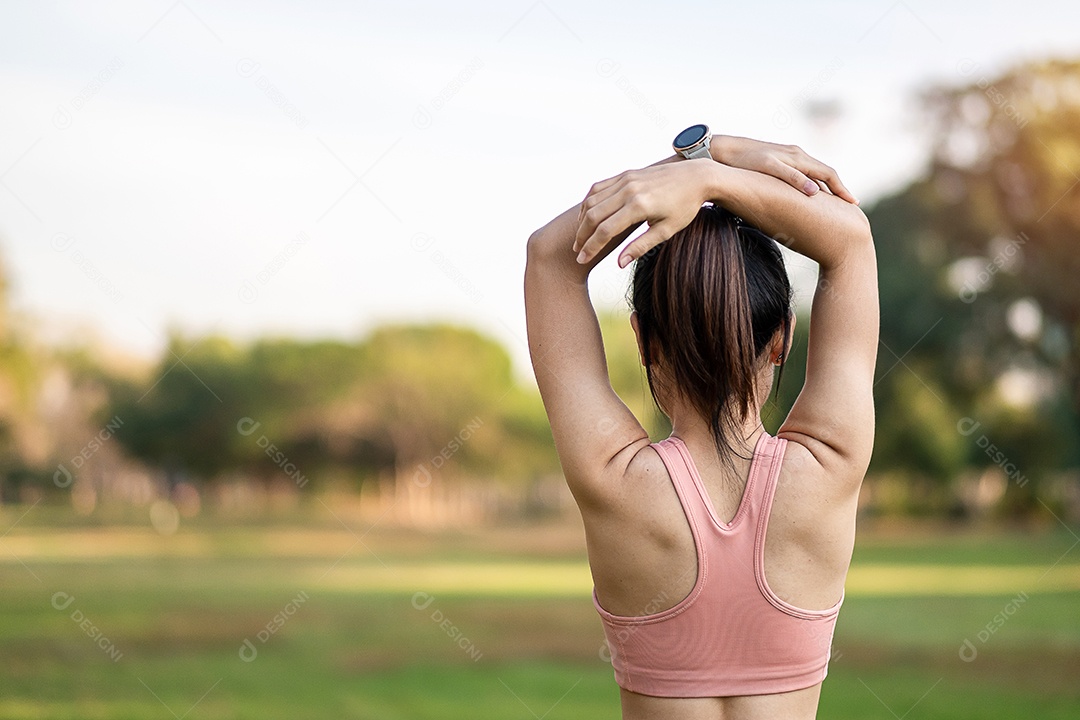 Mulher adulta jovem em sportswear rosa esticando o músculo no parque ao ar livre, esporte mulher aquecer pronto para correr e correr de manhã