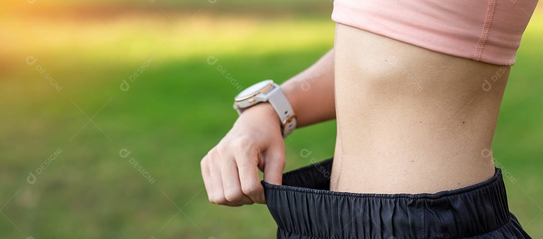 Fêmea jovem de corpo magro em roupas esportivas rosa, mulher saudável com sua cintura fina no parque ao ar livre. Perda de peso