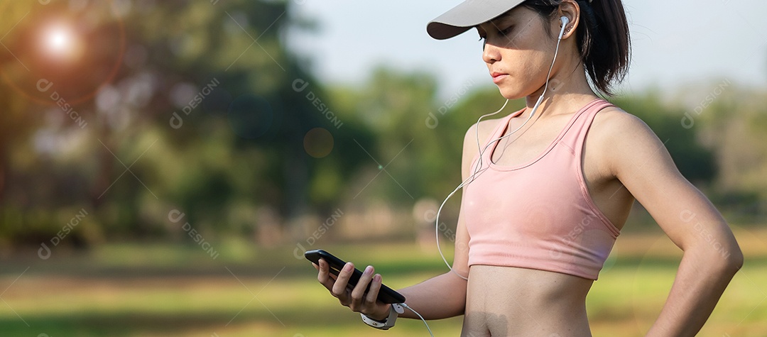 Mulher adulta jovem ouve música no smartphone durante a corrida no parque ao ar livre, mulher corredor correndo pela manhã. Conceitos de exercício