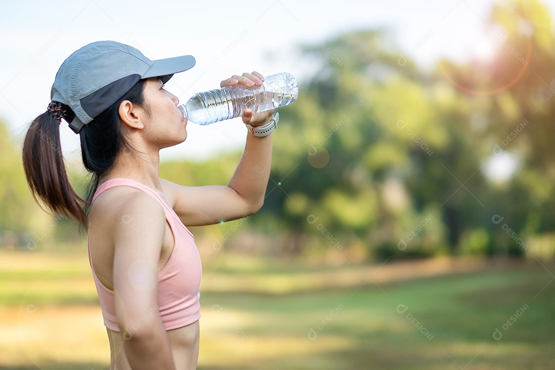 mulher jovem fitness bebendo água energética durante o alongamento muscular no parque ao ar livre, atleta asiático correndo e se exercitando de manhã