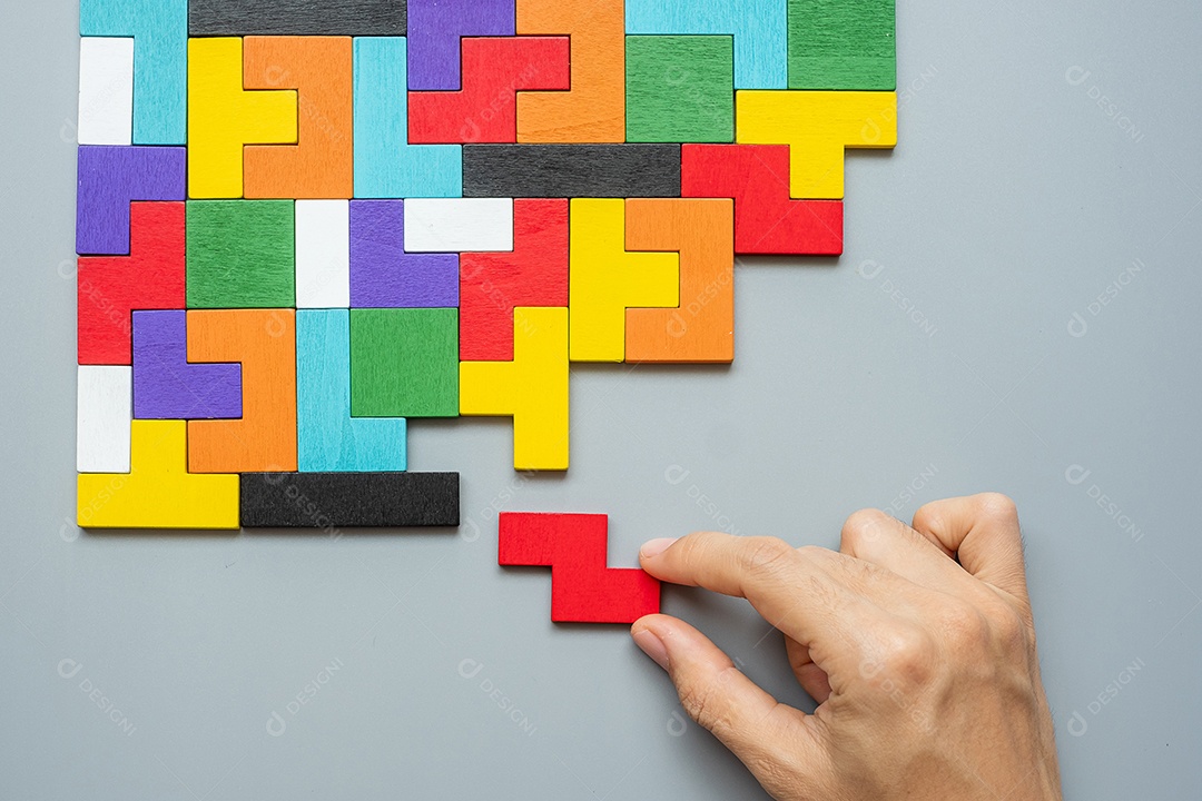 mão conectando o bloco de forma geométrica com peças de quebra-cabeça de madeira coloridas. pensamento lógico, lógica de negócios, enigma