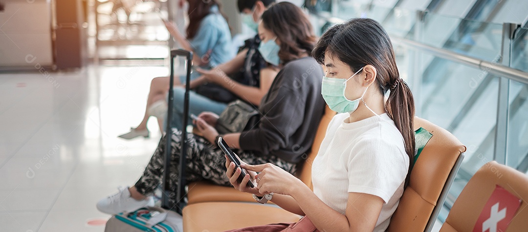 Jovem mulher usando máscara facial e usando smartphone móvel no aeroporto, proteção contra infecção por doença de coronavírus (Covid-19). Novo normal e distanciamento social