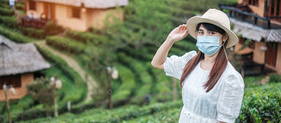 Mulher turista feliz usando máscara facial cirúrgica desfruta de belo jardim de flores, proteção contra infecção por doença de coronavírus