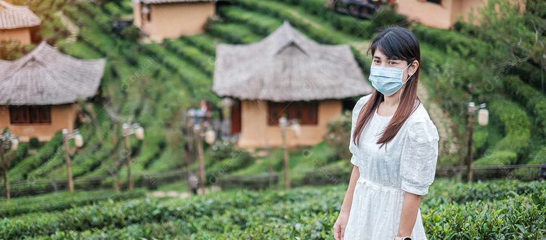 Mulher turista feliz usando máscara facial cirúrgica desfruta de belo jardim de flores, proteção contra infecção por doença de coronavírus