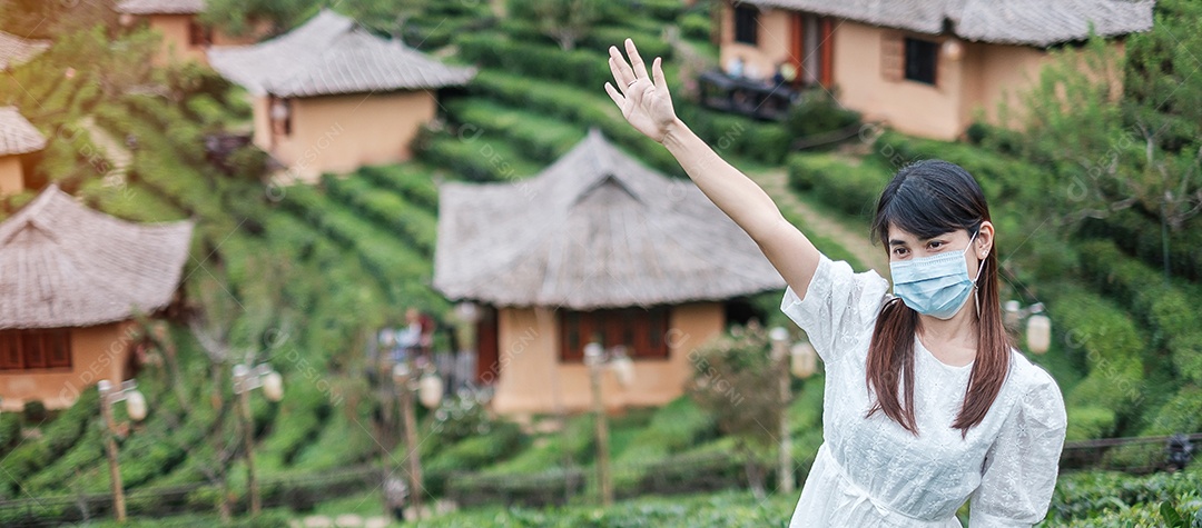 Mulher turista feliz usando máscara facial cirúrgica desfruta de um belo jardim de chá, proteção contra infecção por doença de coronavírus