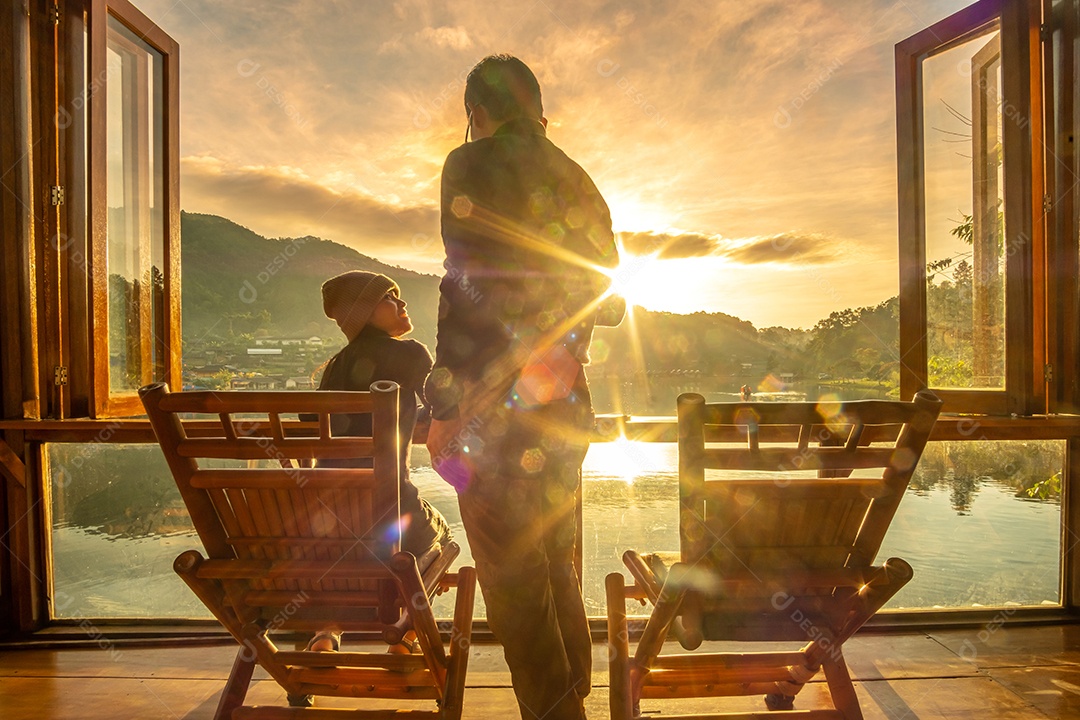 Casal jovem feliz assistindo a vista para o lago no café ao nascer do sol da manhã, vila de Ban Rak Thai, província de Mae Hong Son, Tailândia. Viagens, juntos e conceito romântico